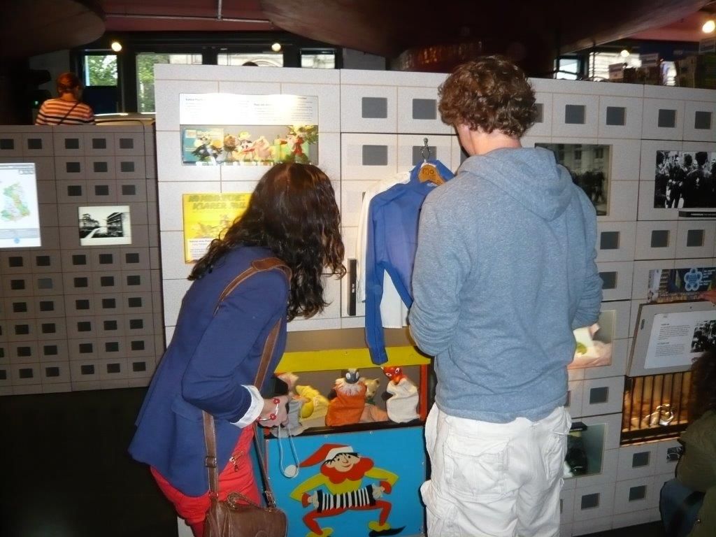 De besøgende er sammen, diskuterer og morer sig mens de åbner og skuffer og skabe for at se, hvad der gemmer sig af genstande og historier.