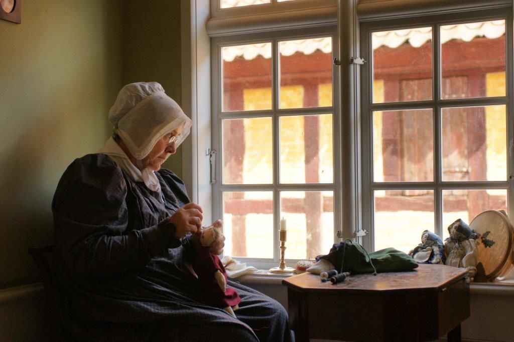 Mange internationale besøgende fascineres af, at Den Gamle By viser tidsbilleder fra en by på H.C: Andersens tid. Her madam Wiberg i Eilschous Boliger, hvor den unge Andersen fik sit første kulturelle hjem, som han selv skriver.