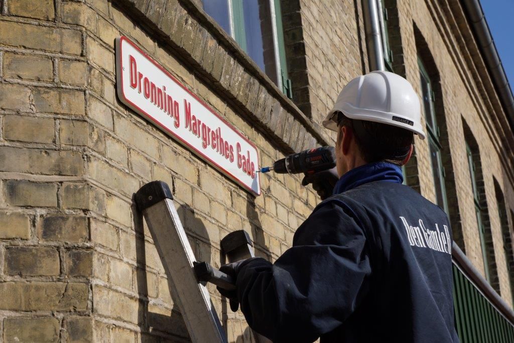 Skiltet med gadenavnet Dronning Margrethes Gade sættes op på huset fra København i Den Gamle By.